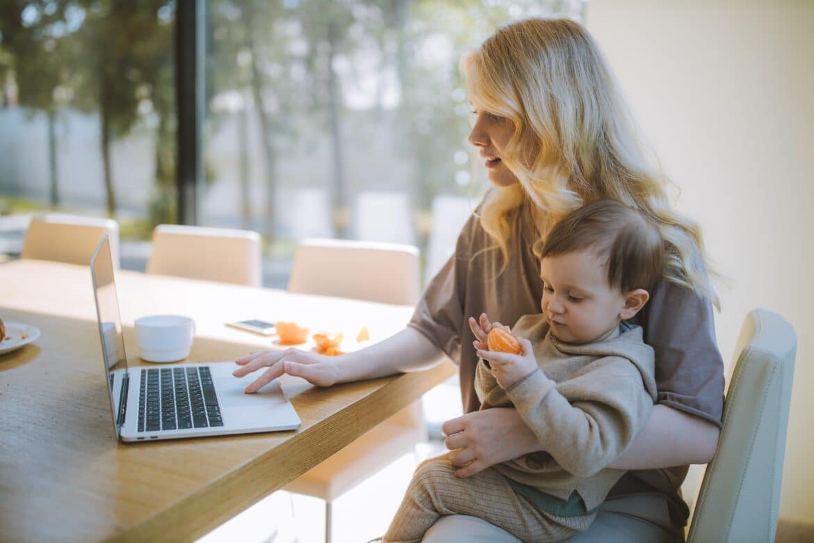 une femme sur son ordinateur avec son enfant sur les genoux